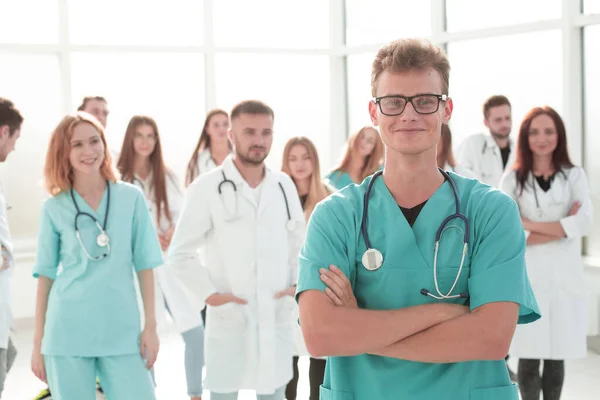 Sorridente giovane medico in piedi davanti ai suoi colleghi anziani . — Foto Stock