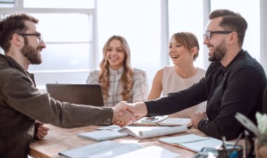 Ofisteki bir toplantıda tokalaşan iş adamları.