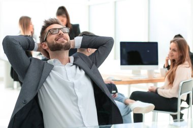 Düşünceli genç işadamı ofis masasında oturuyor.