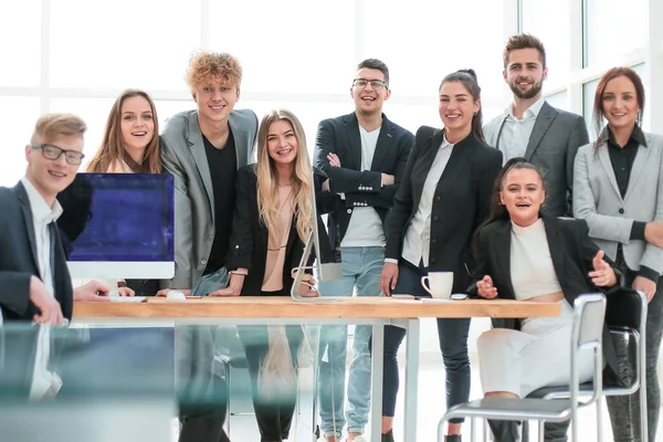 Equipo de jóvenes profesionales de pie cerca del escritorio — Foto de Stock