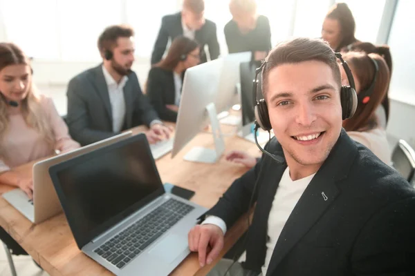 Jovem call center empregado sentado em sua mesa — Fotografia de Stock