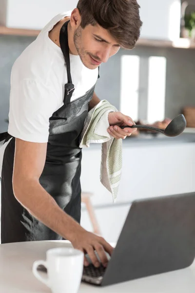 Jonge man het lezen van een recept voor soep in een laptop — Stockfoto