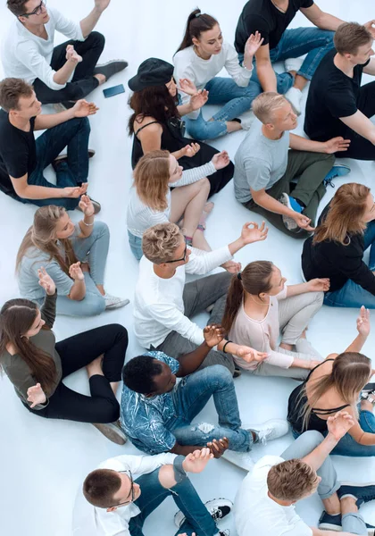 group of diverse young people meditate sitting on the floor.