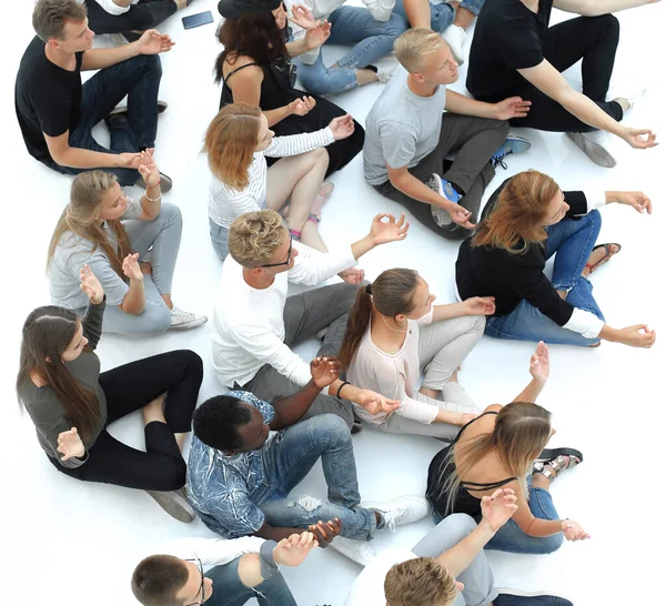 group of diverse young people meditate sitting on the floor.