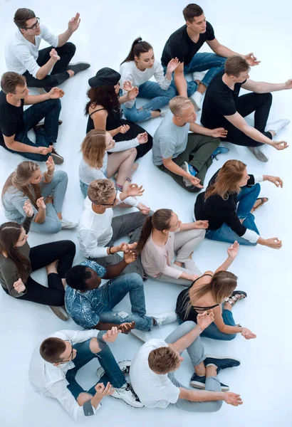 Grupo casual de jovens meditando sentado no chão. — Fotografia de Stock
