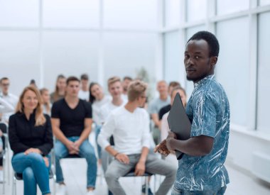 Genç adam iş kursunun öğrencilerinin önünde duruyor.