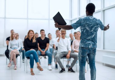 Genç adam iş kursunun öğrencilerinin önünde duruyor.