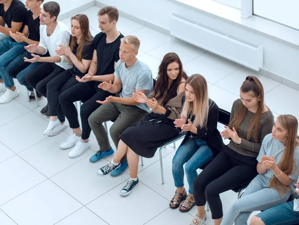 Молоді слухачі бізнес-тренінгу сидять в один ряд — стокове фото