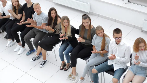 Молоді слухачі бізнес-тренінгу сидять в один ряд — стокове фото