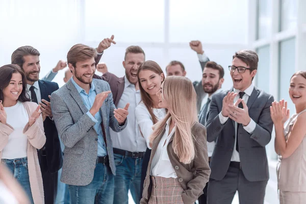 corporate group of employees applauding a young colleague