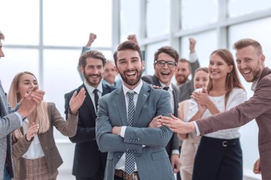 güler yüzlü bir iş ekibi önünde duran emin gururlu işadamı.