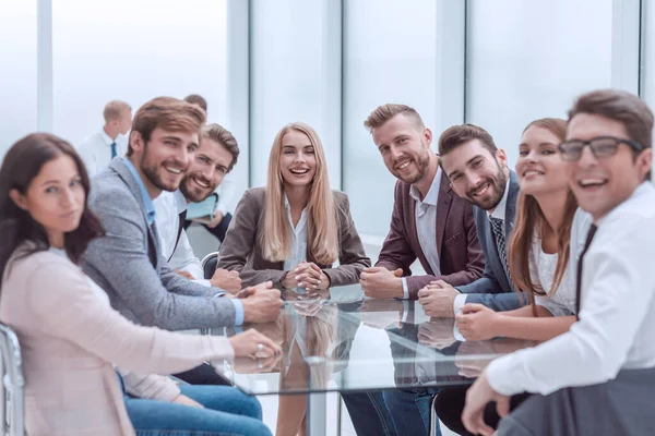 Grupo de jóvenes empresarios sentados en una mesa en una sala de conferencias . — Foto de Stock