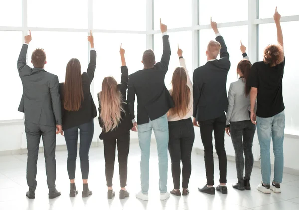 Vista trasera. jóvenes empresarios diversos apuntando hacia arriba — Foto de Stock