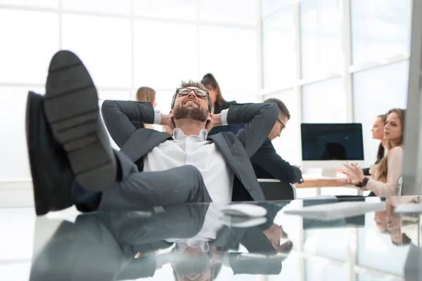 Крупний план. розслаблений бізнесмен сидить зі своїми ногами на столі . — стокове фото