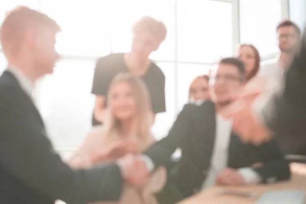 Wazig imago van zakenmensen die elkaar de hand schudden op een bureauvergadering. — Stockfoto