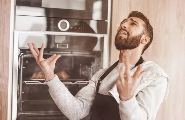 Förvånad man står nära ugnen med brända croissanter. — Stockfoto