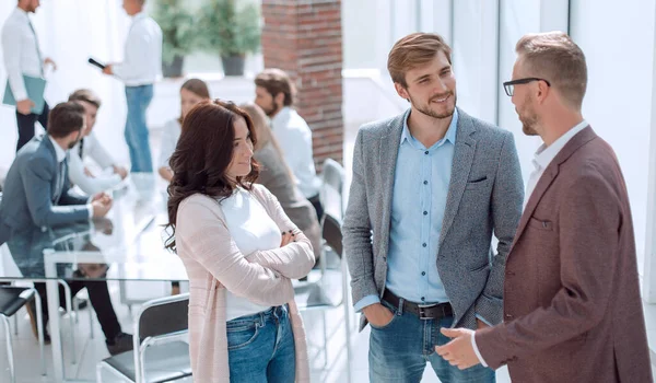 Tres jóvenes empleados de pie en una oficina moderna. — Foto de Stock