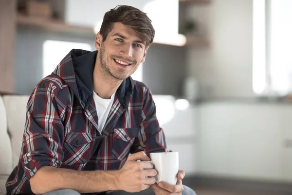 Ung man med en kopp kaffe i bakgrunden i köket — Stockfoto