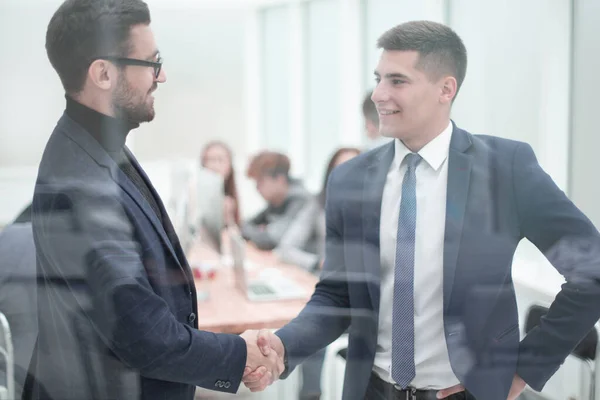 Durch das Glas. Geschäftspartner per Handschlag im Büro — Stockfoto