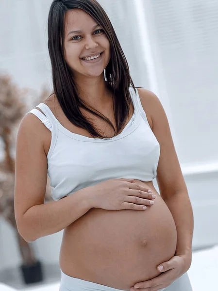Portret van jonge zwangere vrouw op een lichte achtergrond. — Stockfoto
