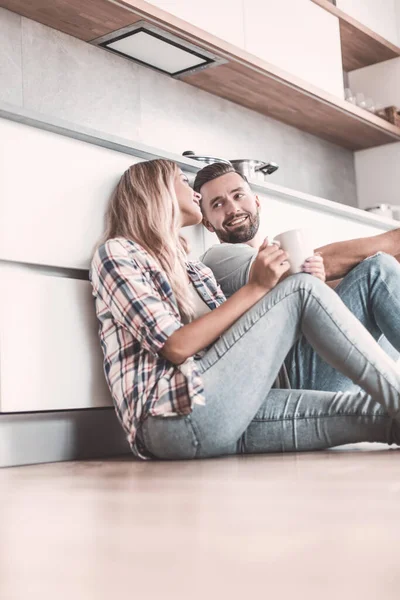 Pareja joven tomando café sentado en el suelo de la cocina —  Fotos de Stock