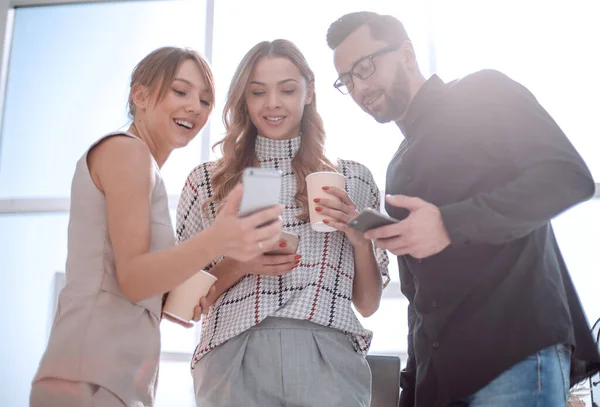 Equipe de negócios olhando para as telas de seus smartphones — Fotografia de Stock