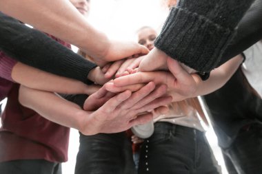 Bir grup farklı genç insan ellerinden bir kule yapıyorlar.