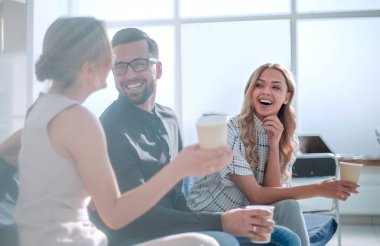 Kahve bardaklı şirket çalışanları lobide oturuyorlar.