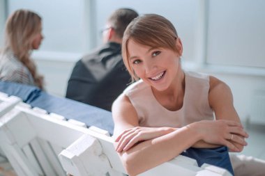 Elinde kahve fincanı olan genç bir iş kadını lobide oturuyor.