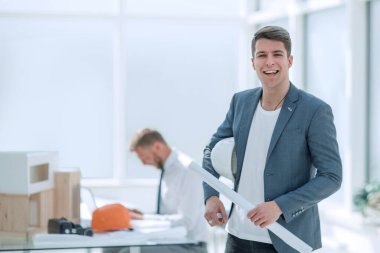 Gülümseyen mimar parlak bir ofiste duruyor..