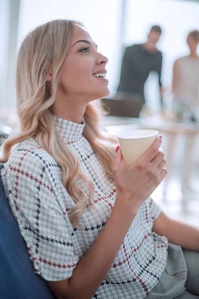 Jovem mulher de negócios com uma xícara de café em um escritório moderno — Fotografia de Stock