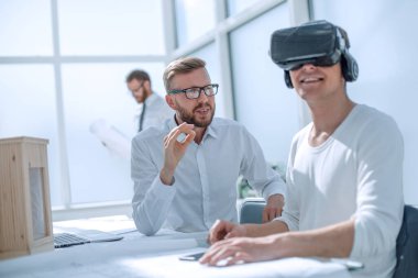 Kapat. VR kasklı tasarımcı masasında oturuyor..
