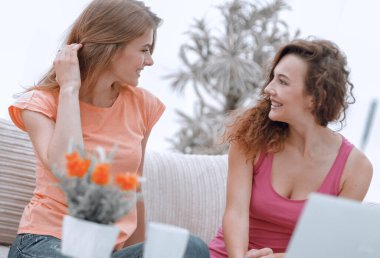 İki genç kadın kahve masasında konuşuyor ve oturuyor.