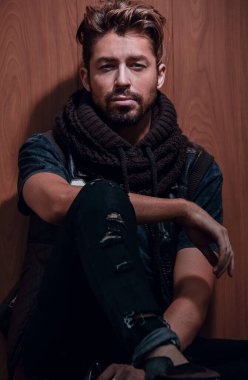 Sıradan giyinmiş sakallı bir adam oturur.