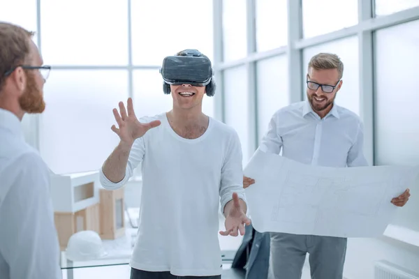 Joven diseñador en casco de realidad virtual de pie en la oficina de arquitectura —  Fotos de Stock