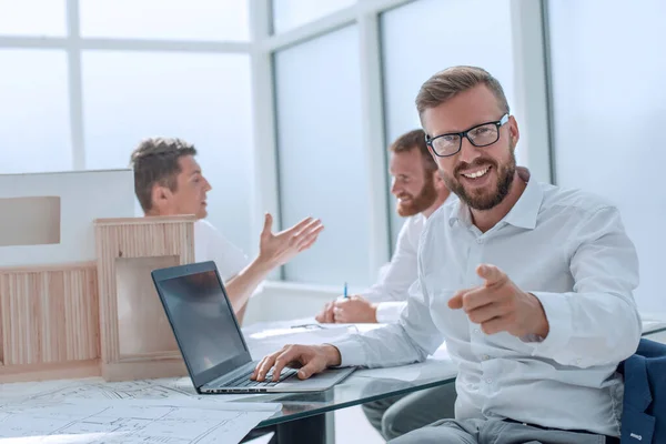 Diseñador de interiores sentado en su escritorio y apuntando a usted . — Foto de Stock