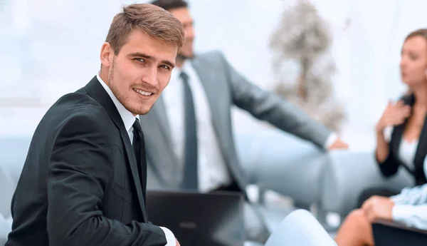 Sikeres jóképű üzletember ül a munka íróasztal homályos háttér — Stock Fotó