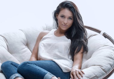 Yuvarlak, yumuşak bir sandalyede oturan modern genç kadın.