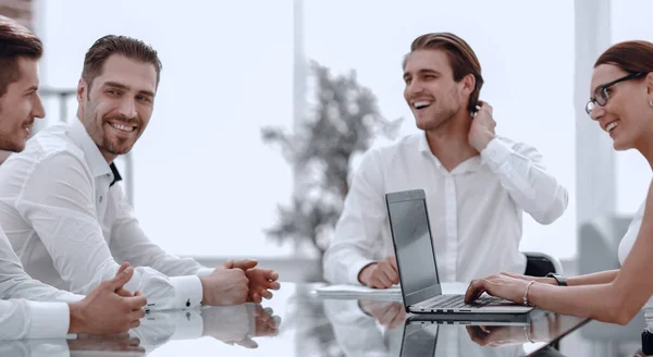 Sonriente equipo de negocios sentado en el escritorio . — Foto de Stock