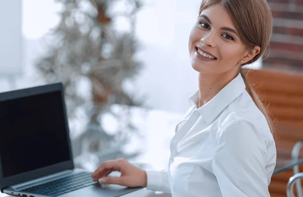 Giovane donna d'affari seduta alla scrivania in un ufficio, che lavora su un computer portatile — Foto Stock