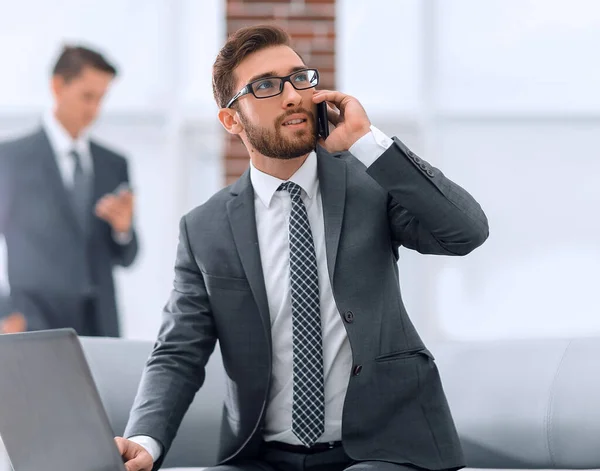 Confident young man talking on phone in office — Stock Photo, Image