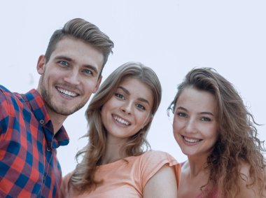 Beyaz arka planda gülümseyen üç genç insana yakın çekim