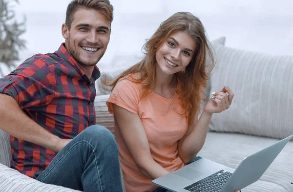 Par de estudantes com um laptop sentado no sofá — Fotografia de Stock