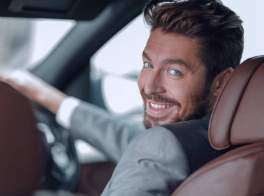 Dikiz aynası, genç adam arabasını sürüyor, kameraya bakıyor.