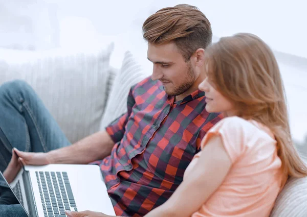 Young man and girl with laptop sitting on sofa — Stock Photo, Image