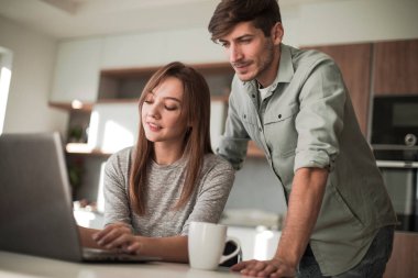 Evde, mutfakta dizüstü bilgisayar kullanan sevimli bir çift.