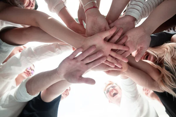 Ansicht von unten. Ein Team junger Leute bastelt einen Turm aus ihren Händen. — Stockfoto