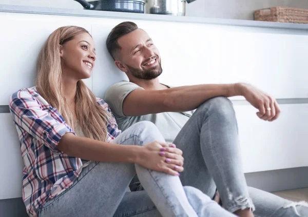 Casal feliz discutindo algo sentado no chão da cozinha — Fotografia de Stock