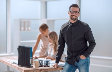 Gülümseyen genç iş adamı ofiste duruyor.