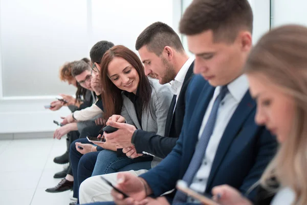 Fiatal alkalmazottak nézik az okostelefon képernyőiket — Stock Fotó